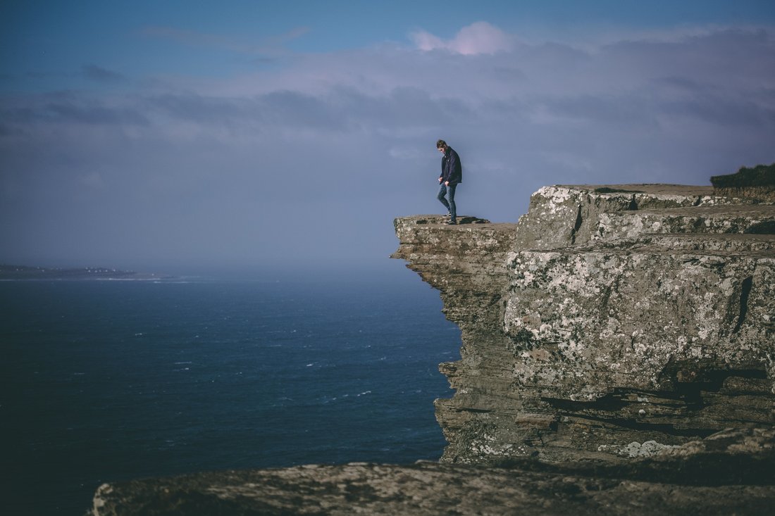 A lone figure standing at the edge of a sea cliff
