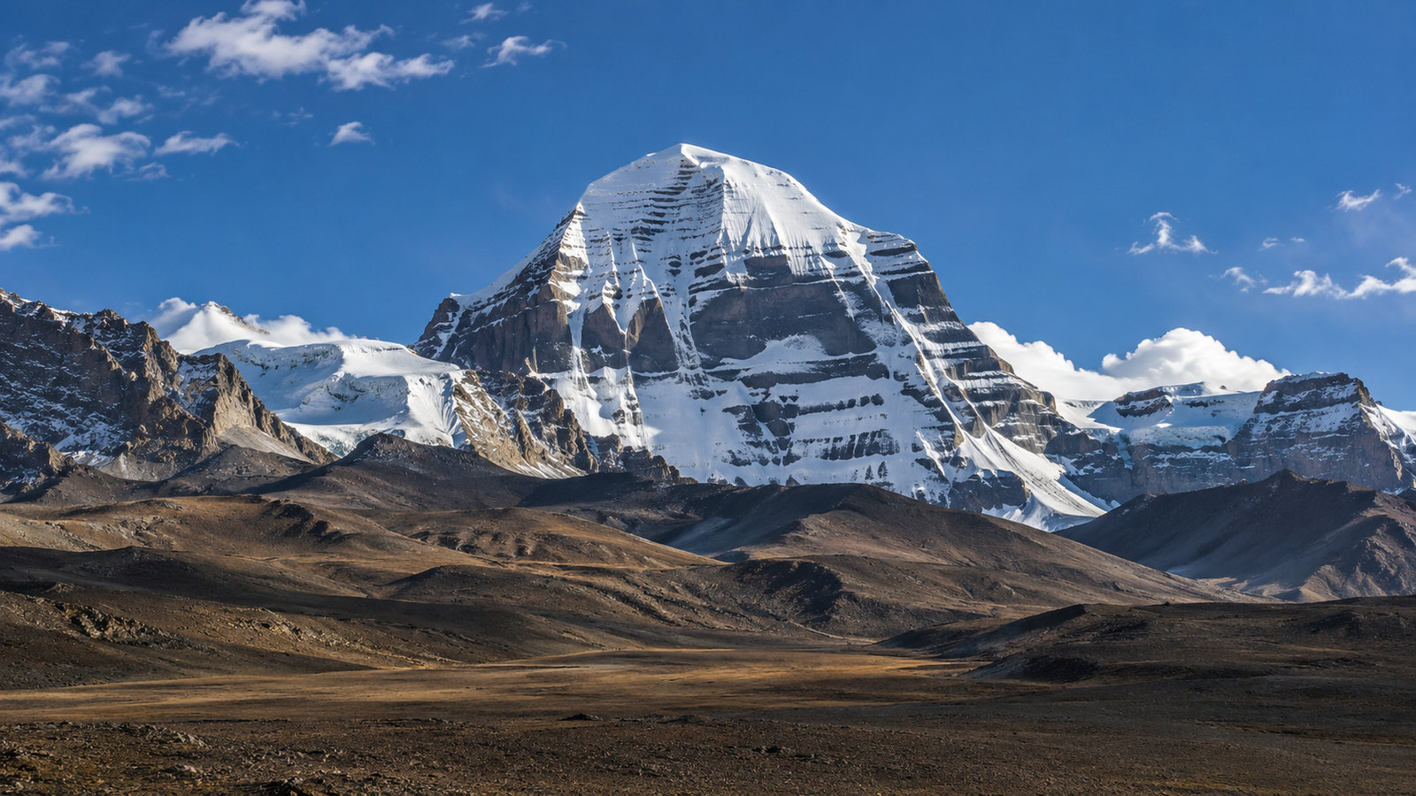 The snow-covered, pyramid-shaped face of Mount Kailash rising above the high plateau